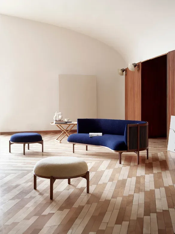 A living room with a blue sofa and ottoman in scandinavian design.