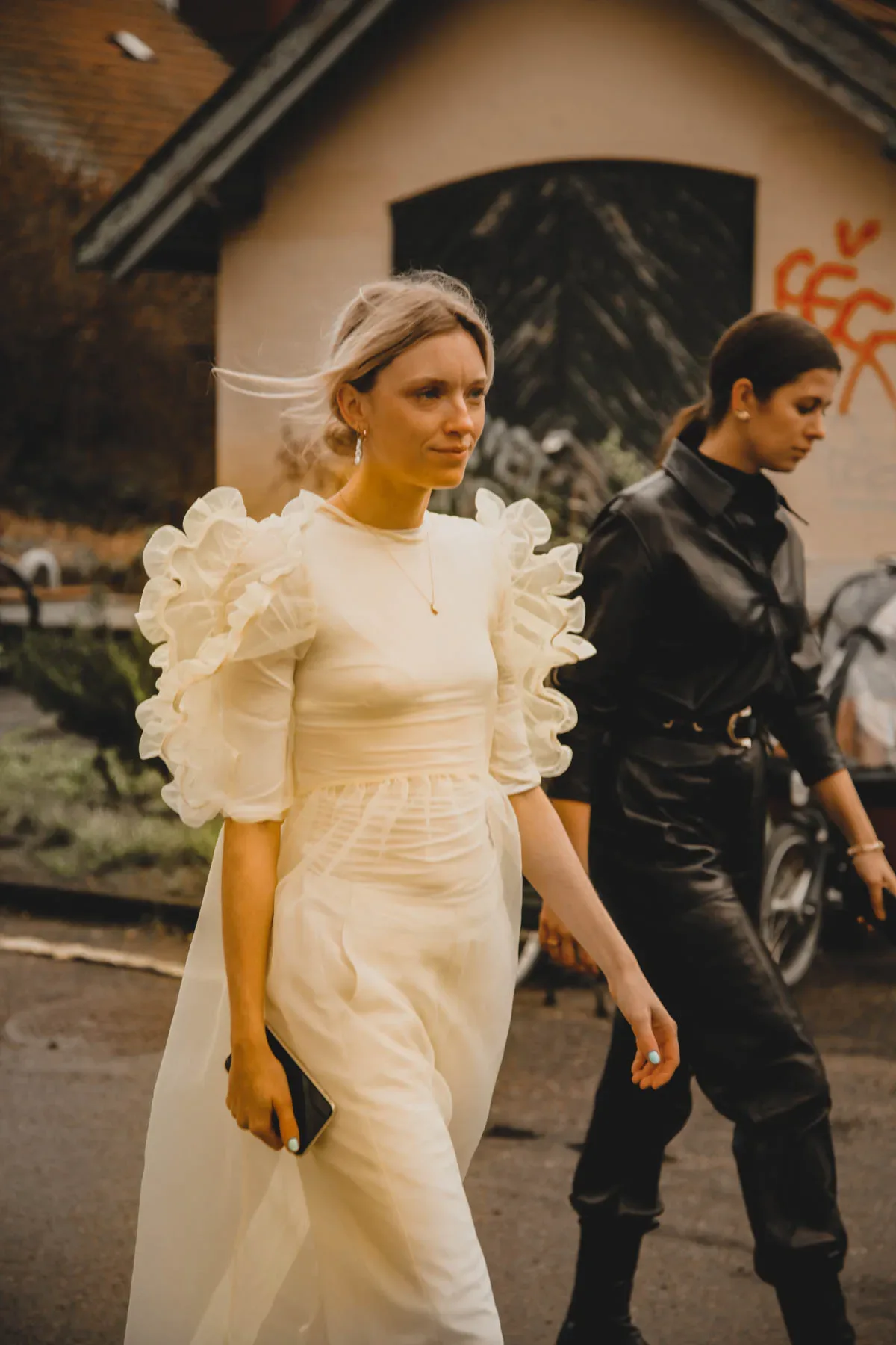 Two Scandinavian women walking down the street in a white dress.