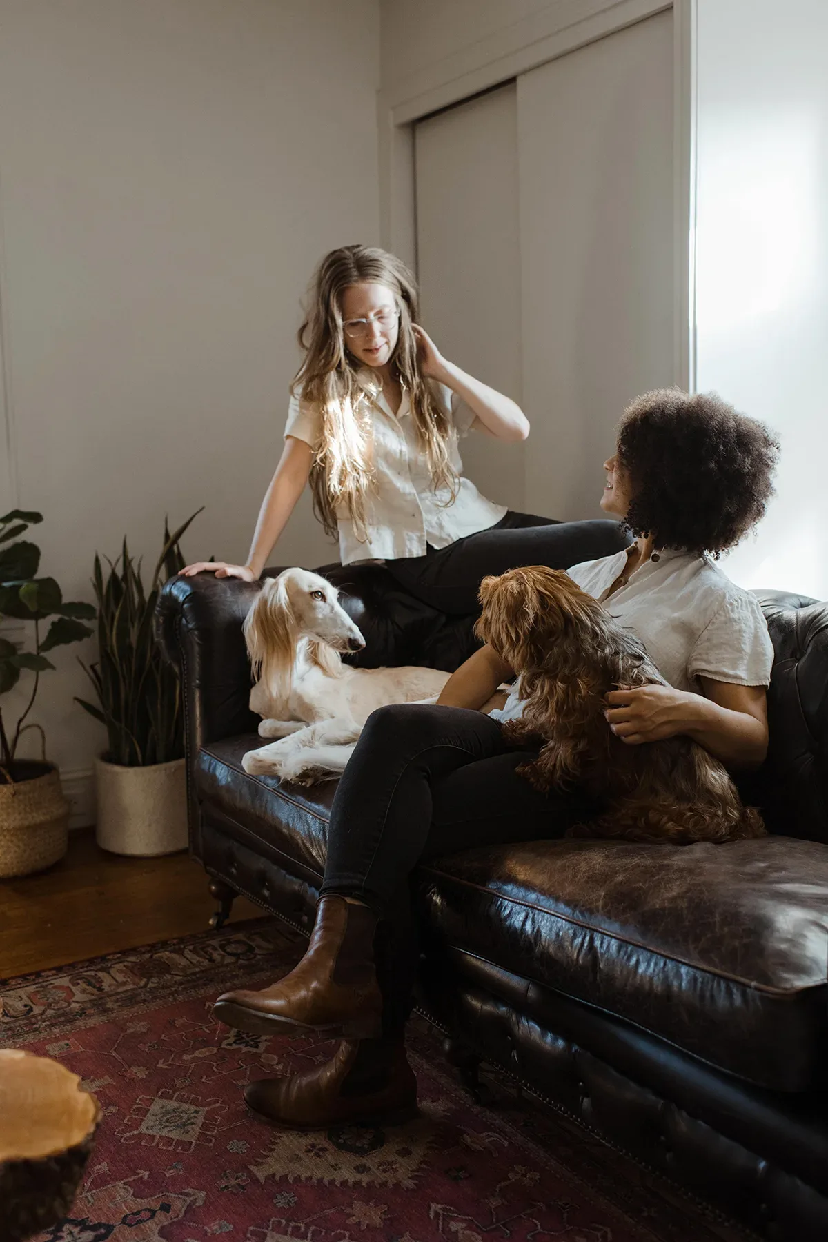 Two Scandinavian women in a relationship sitting on a couch with two dogs.