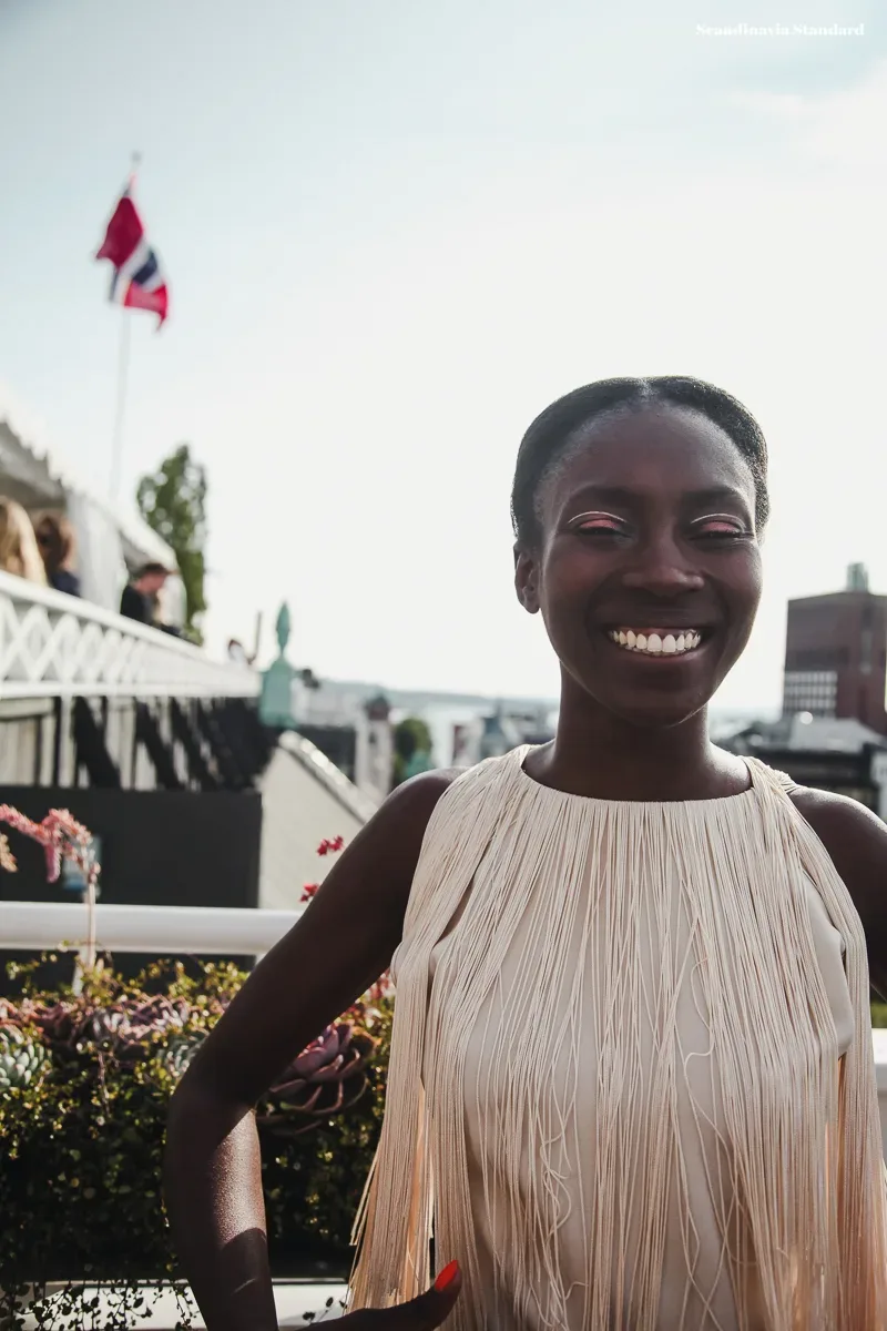 A Scandinavian woman is smiling in front of a crowd of people.
