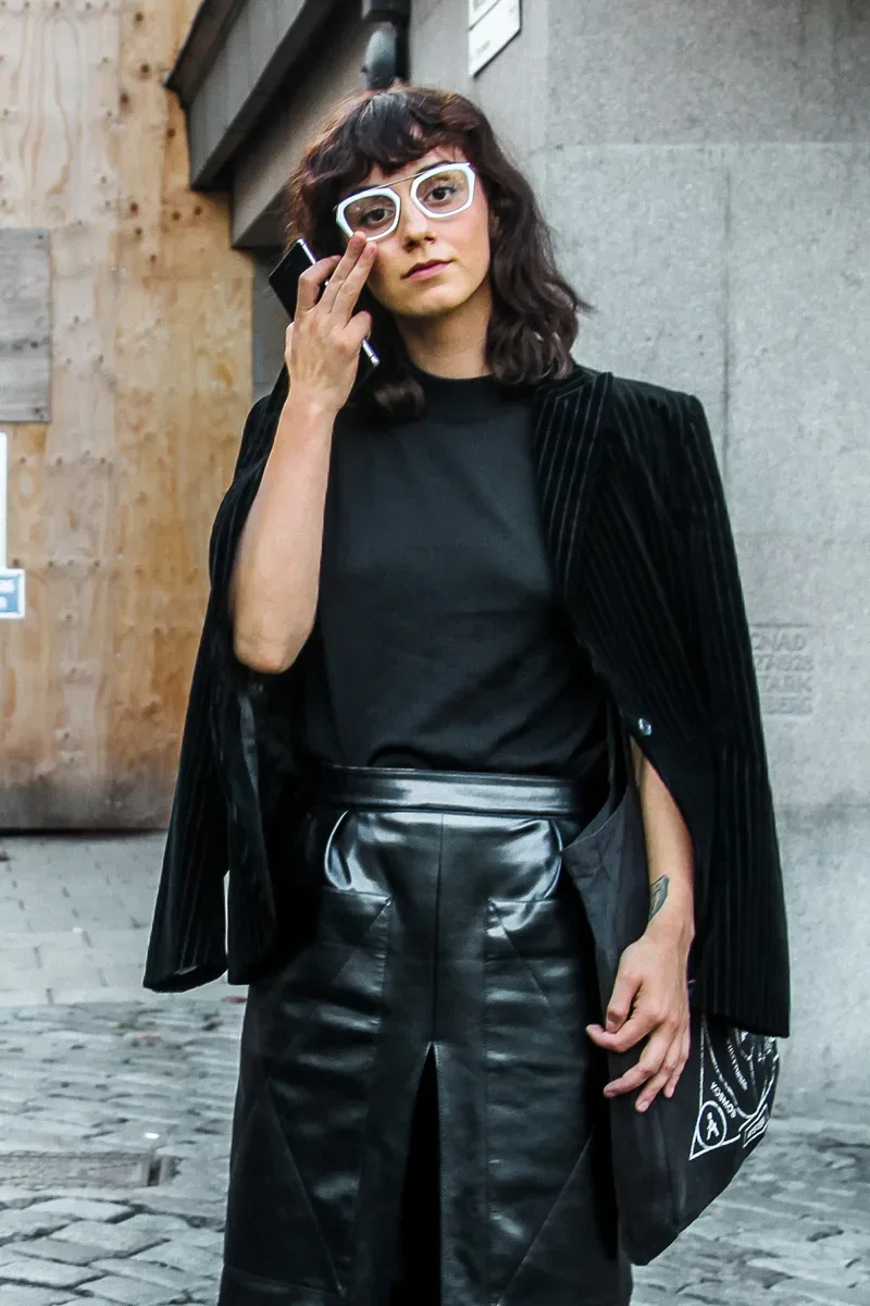 A Scandinavian woman in a black leather skirt and a black blazer.