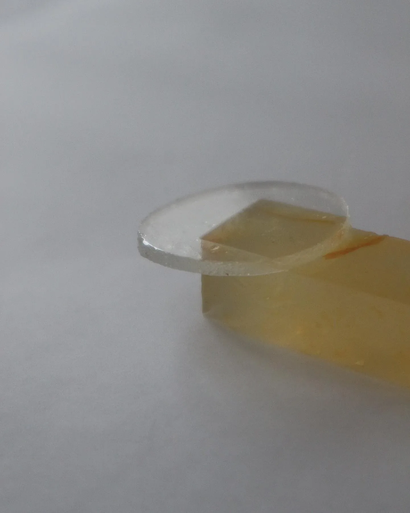 A piece of yellow glass sitting on top of a white surface, reflecting the vibrant colors of the sun.