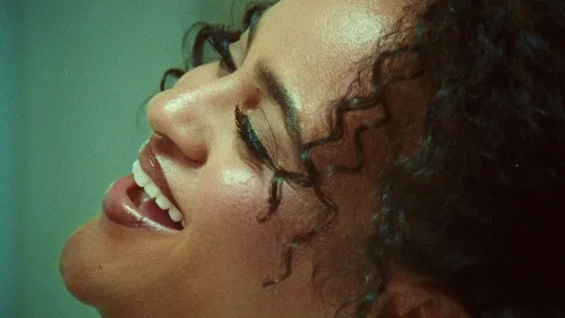 A woman with curly hair is smiling.
